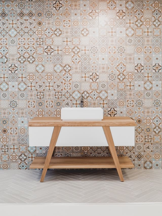 hout en witte wastafel in een spaanse badkamer met mozaiëk tegels